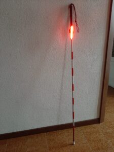 A red and white cane with a flashing light