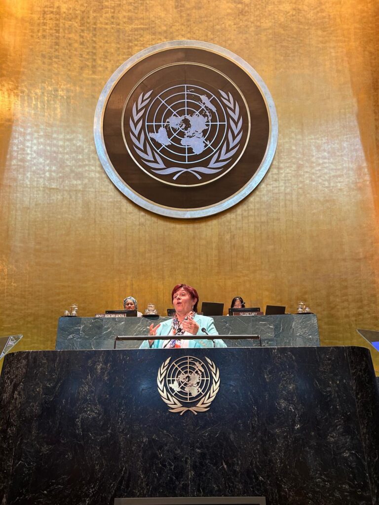 A woman behind at a stage, with the UN symbol behing