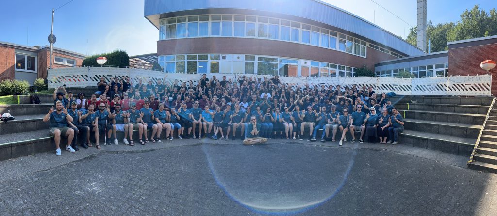 Panoramic shot of EDBY Camp participants, all seated on steps and wearing the same dark blue t-shirt.