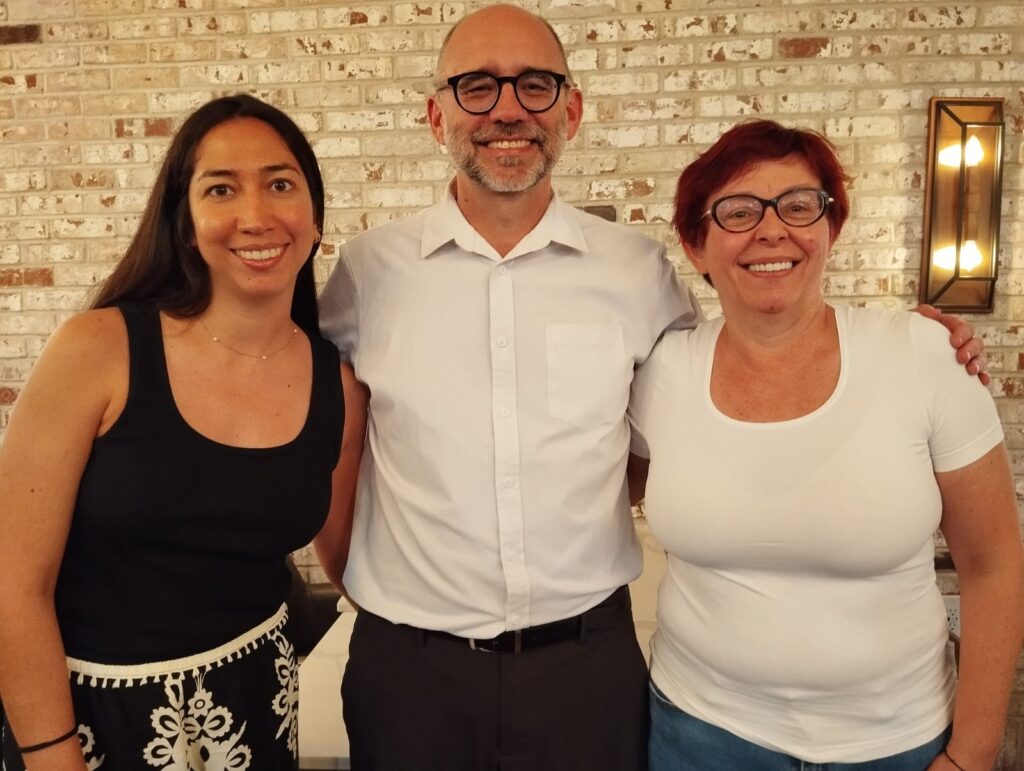 Two women and a man smile at the camera