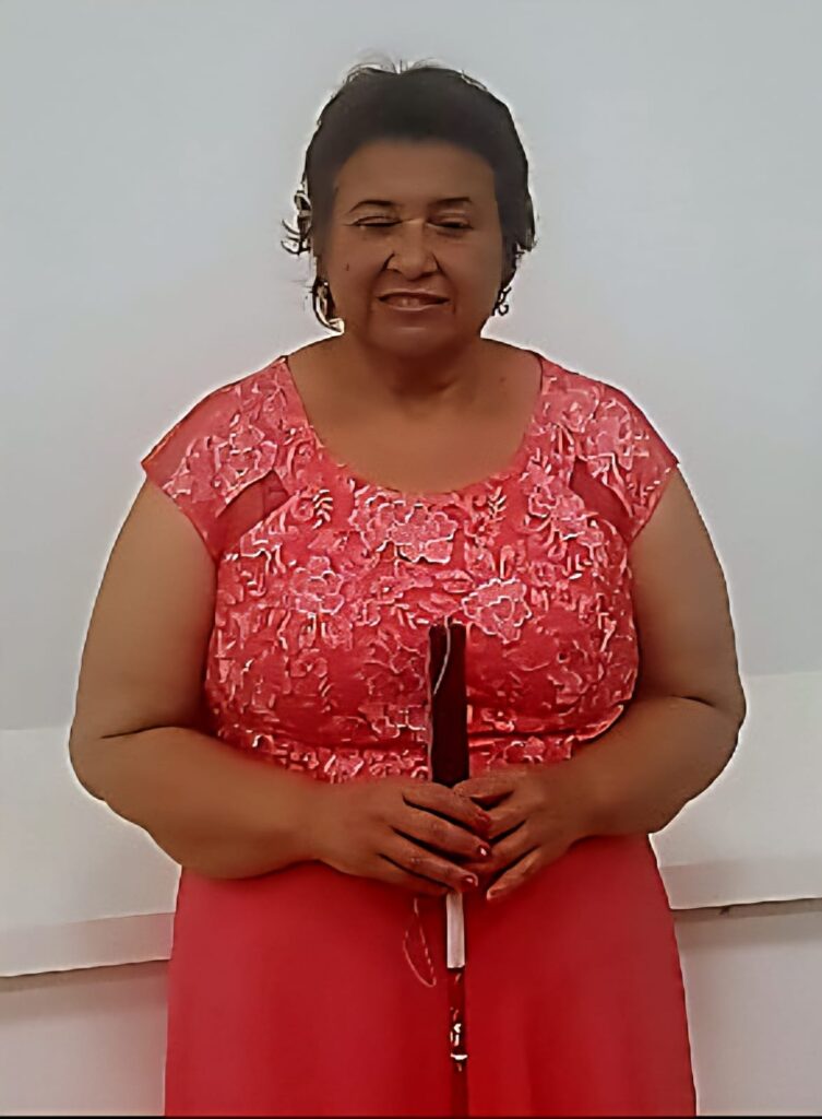 Eulalia is smiling whilst holding a a cane wearing a red dress